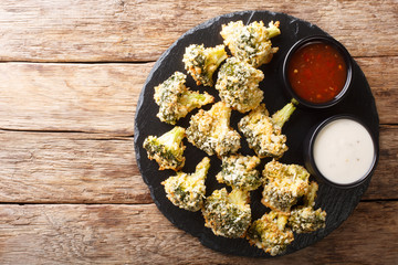 Healthy appetizer broccoli sticks in cheese breading baked served with sauces. Horizontal top view
