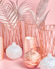 beautiful composition of round candles, ceramic and metal candlesticks, palm leaves in rose gold on a pink background. the trend for home decor, close-up