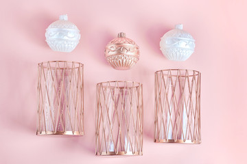 candles in the form of balls of white and copper color. metal candlesticks on pink background. modern home decor. simple flat layout, top view