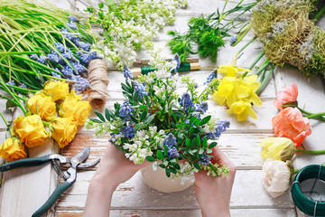 Florist at work: woman arranging bouquet of springtime flowers.