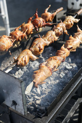 Grilled chickens on a spit. Rotisserie chicken. Brazier and coals.