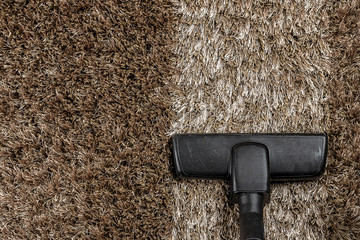 The head of vacuum cleaner on shaggy carpet with an extra clean strip. House cleaning. Domestic...