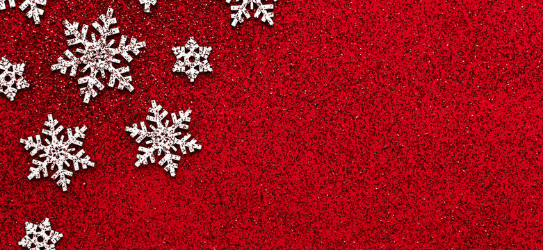 Merry christmas concept white snowflakes on red glitter background table minimal flat lay with red glitter, winter holiday party event card, horizontal photo design postcard banner, copy space