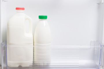 bottles with kefir and milk stand on a shelf in the door of a white open refrigerator