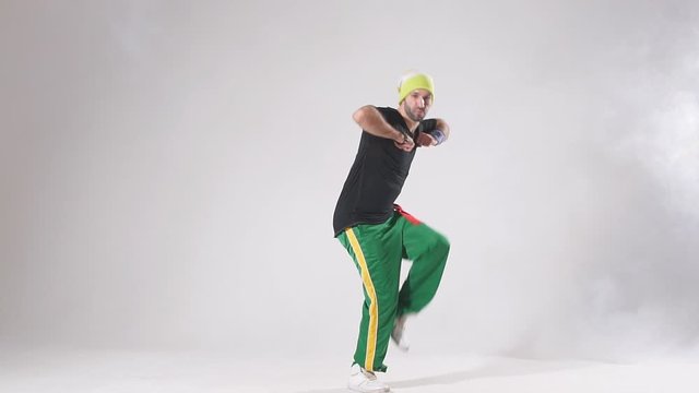 Professional male hip hopper in motion standing on light coloured floor of spacious dance hall, enjoying hip hop dance