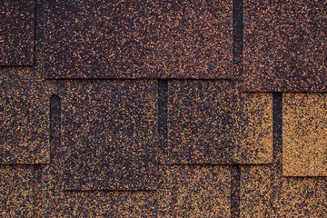 Dark brown and yellow surface of roofing tiles. Cover of shape of squares. Dark roof tile, grunge texture. Brick wall background.