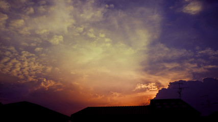 Silhouette light from the sky at sunset turn orange With cloud and the roof of the house was blocked.