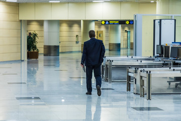 Businesman or inspector in strict costume from the back in the airport or raiway station going to the registration hall with the inscription in Russian and chinese meaning registration