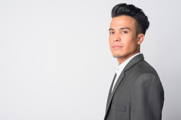 Closeup profile view of young Asian businessman in suit looking at camera