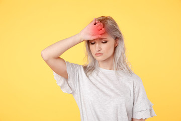 Sad stressed young woman feelin headache standing in the yellow studio