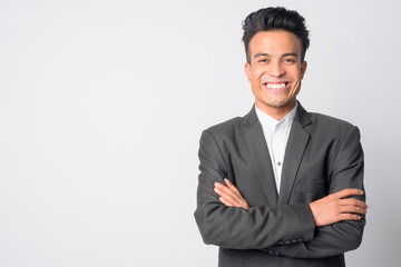 Portrait of happy young Asian businessman in suit smiling with arms crossed