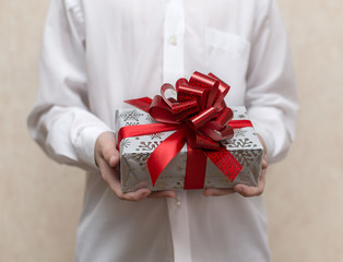 a child in a white shirt holds a gift in a box with a red bow