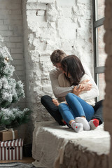Loving couple on a light background celebrates Christmas. Love, cares, warmth.