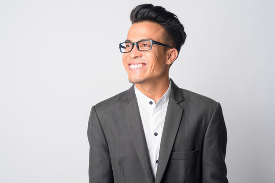 Face of happy young Asian businessman with eyeglasses thinking
