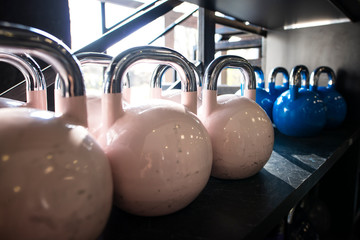 Kettlebells lined up on shelf in gym ready to be used for weight lifting and training.
