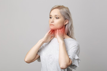 Female checking thyroid gland by herself. Close up of woman in white t- shirt touching neck with red spot. Thyroid disorder includes goiter, hyperthyroid, hypothyroid, tumor or cancer Health care.