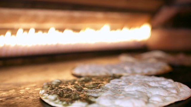 Making Manakeesh inside a gas heated oven, slow motion. Manakeesh is a type of pastry, which is a popular Lebanese and Levantine food consisting of dough topped with thyme, cheese or meat