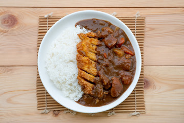 Tonkatsu, Japanese deep-fried pork cutlet on top with curry in white dish on wooden table. Japanese food.
