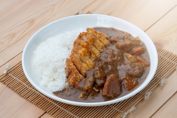 Tonkatsu, Japanese deep-fried pork cutlet on top with curry in white dish on wooden table. Japanese food.