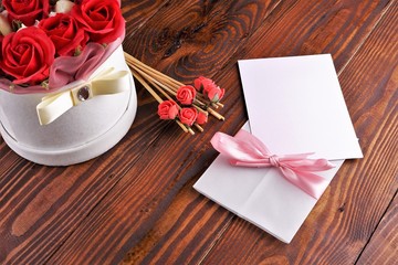 Gift box with flowers on wooden background, preparation for the holiday concept. Top view and copy area for text.