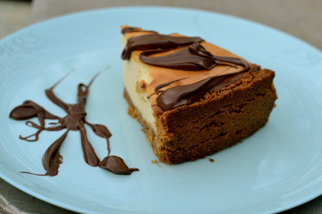 Delicious classic cheesecake with cottage cheese and chocolate sauce on a blue plate 