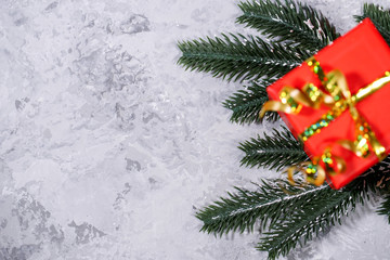 New Year or Christmas present, red box wrapped on a gray background with fir branches. Holiday, surprise. Background. Flat lay, top view, space for text.