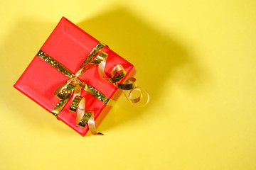 gift, red box packed on a yellow background, close-up. Holiday, New Year, Christmas, surprise. Flat lay, top view, space for text.