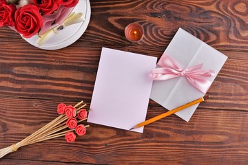 Gift box with flowers on wooden background, preparation for the holiday concept. Top view and copy area for text.
