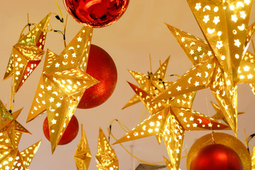 Decorated lighting golden stars and big red Christmas balls hanged on ceiling in the room for ready on the Christmas night party.