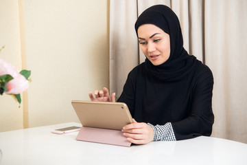 Arabic woman using tablet pc computer. Southeast Asian student at home. Muslim teenage girl living lifestyle.