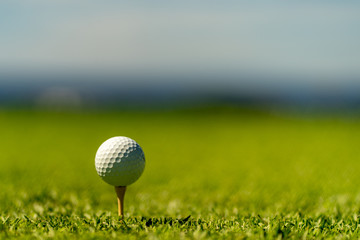 white golf ball on a tee with blurry background