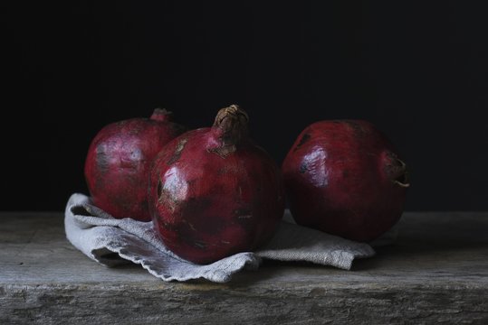 Still life photography shot of three gorgeous pomegranates on a wooden deck