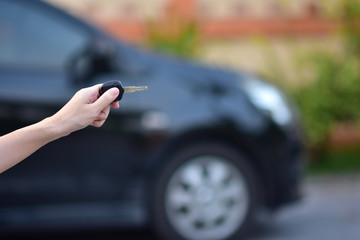 Salesman holding Key of car and car parked  background