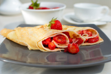 Rolled crepes or balkan pancakes stuffed fresh chopped strawberries