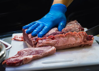 Butcher Cutting Raw Meat With Knife in the kitchen