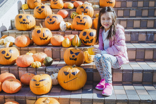 Cute Asian girl with pumpkins during Halloween