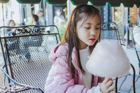 Cute Asian girl sitting and eating candyfloss