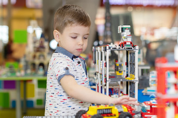 Little boy playing toy cars. Young kid with colorful educational vehicle and transport toys. Child driving car to rainbow parking garage. Kids at home or daycare. Kindergarten or preschool game.