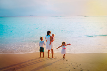 mother with kids looking at sunset on beach