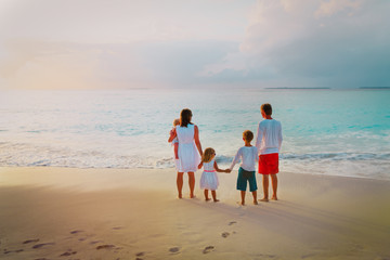 happy family with kids looking at sunset on beach