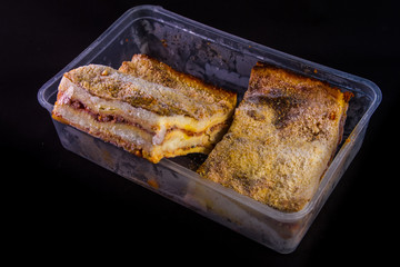 frozen homemade lasagna on a wooden cutting board with basil leaf and the pan with frost