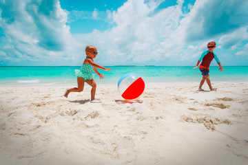 little girl and boy play ball on beach