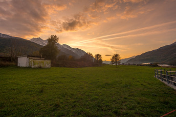 Countryside landscape with mountains in the background at sunset. Yellow and red sky with clouds