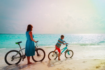 Fototapeta premium mother and son riding bikes on tropical beach