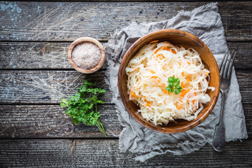 Homemade sauerkraut with carrots in a bowl on wooden table. Vegetarian vegan food. Top view