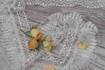 White wooden background with white spring flowers roses and lace ribbon. Happy womans day. The...