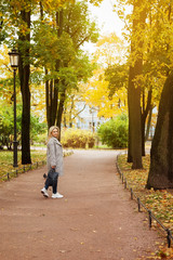 Portrait of a young woman walking down the alley in autumn