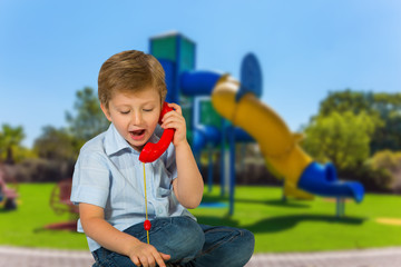 Boy is talking on a toy red telephone