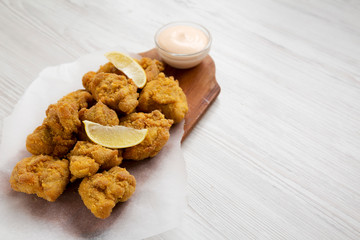 Homemade crispy japanese fried chicken Karaage on a rustic wooden board over white wooden background, low angle view. Copy space.