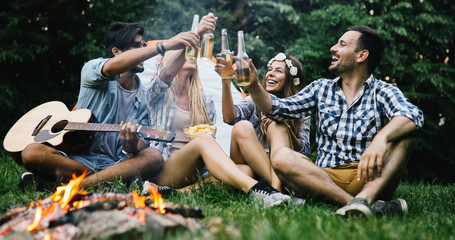 Obraz na płótnie Canvas Happy friends playing music and enjoying bonfire